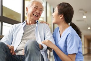 friendly caretaker talking to senior patient in nursing home