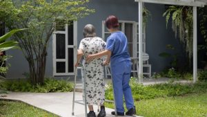 Caregiver and elderly woman walking outside